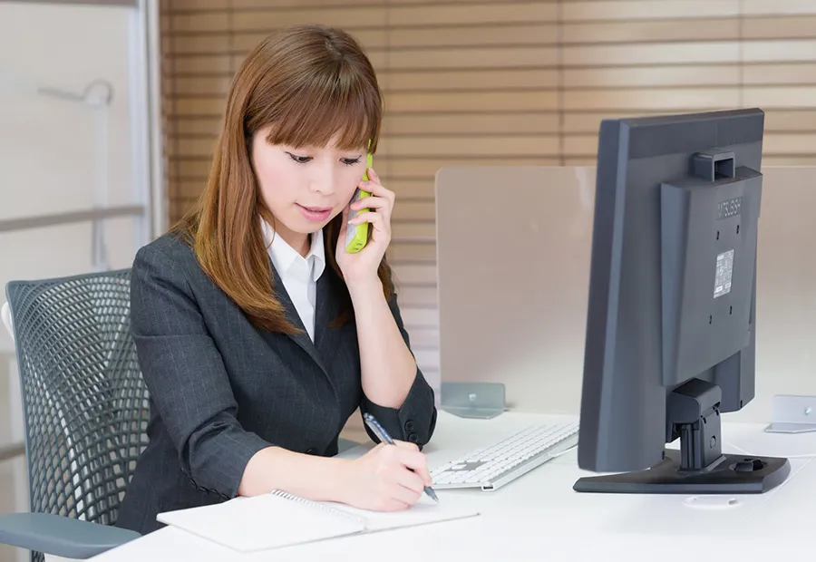 電話をしながらメモを取る女性